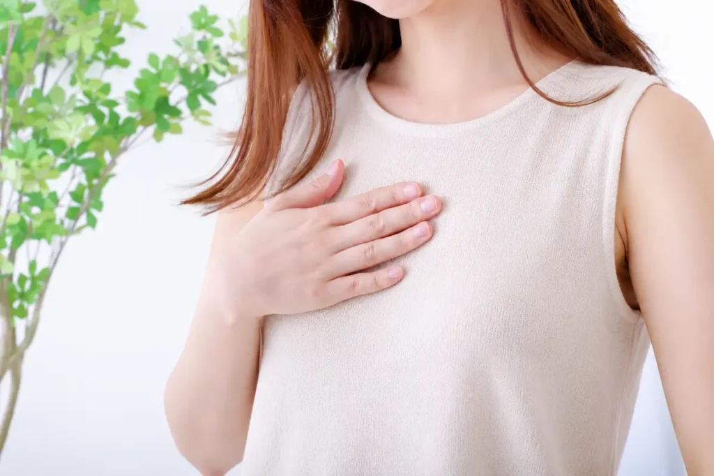 狭心症の発作を起こし、胸に手をあてている女性